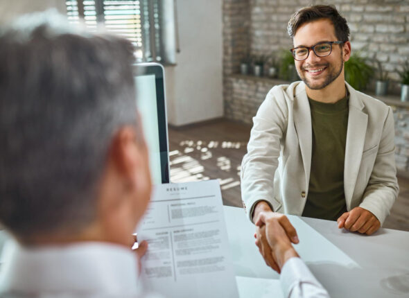 candidato-masculino-feliz-saludando-miembro-equipo-recursos-humanos-entrevista-trabajo-oficina