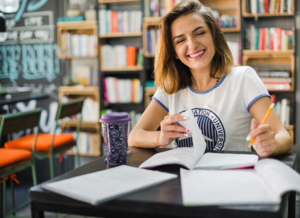 sonriente-nina-sentada-mesa-cuadernos